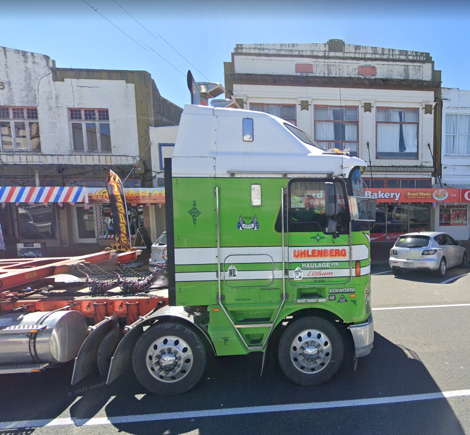 A lime-green 
cabbed van driving past the old Malloy's shop in Stratford's main road.