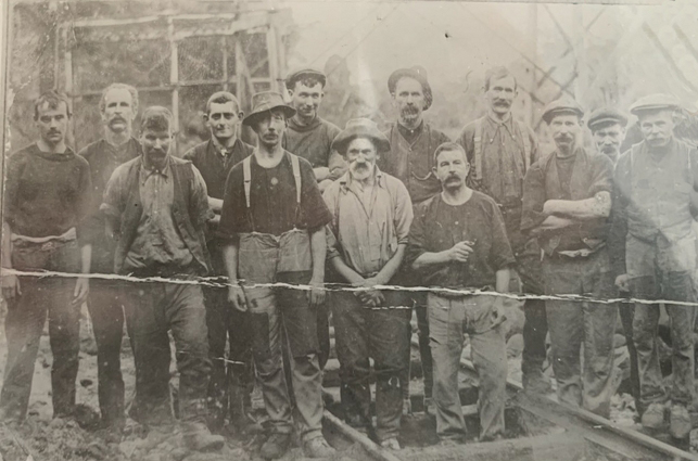 A group of labourers 
standing on a railway line. No other visible landmarks.