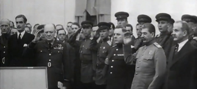 Stalin and Churchill 
standing among military personnel and saluting the sword