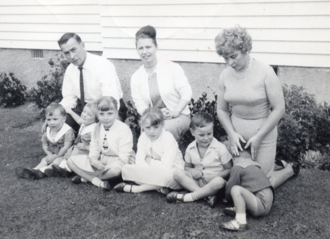 Zioło siblings, 
each with two children, sitting on the grass in front of a house.