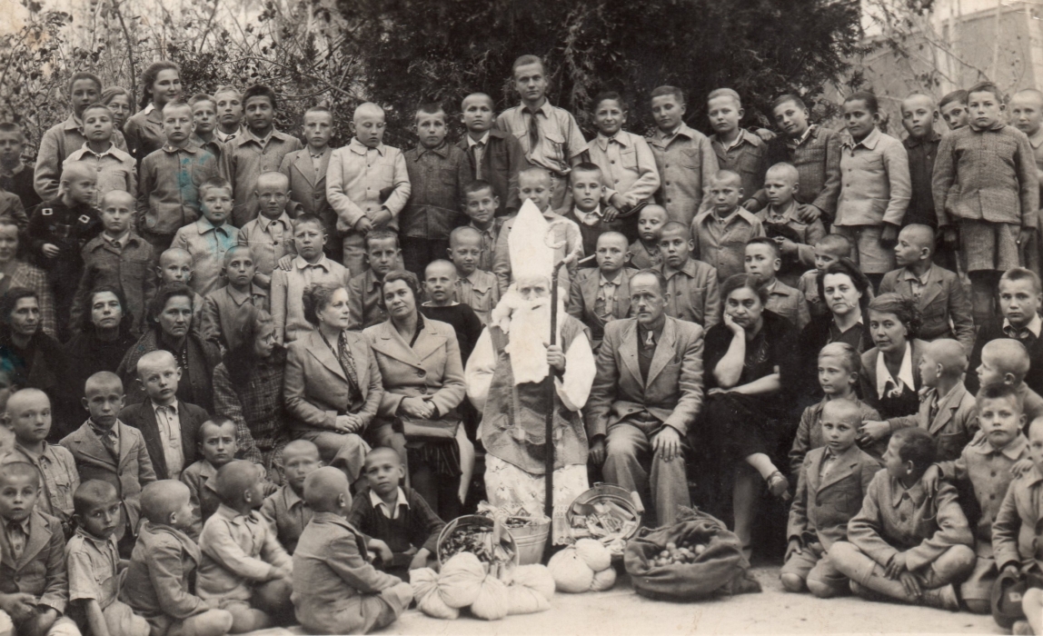 A large group of 
mostly serious Polish children, with at least nine adults, surround St Nicholas.