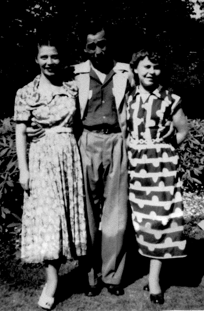 Black and white 
photograph of Danuta, Tadeusz and Alina, taken outside in a garden.