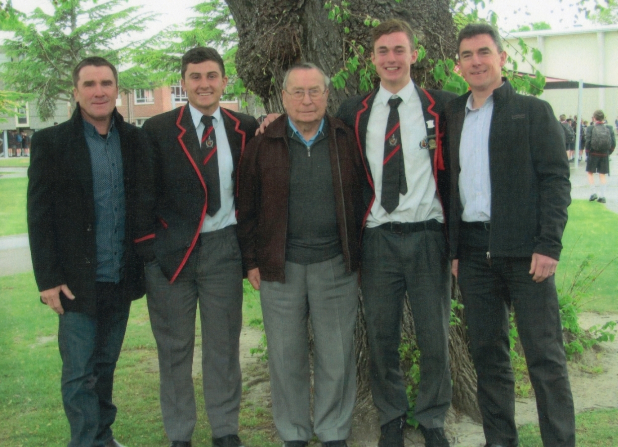 Tadeusz between 
his sons and grandsons, taken under a tree, grandsons in school uniform.