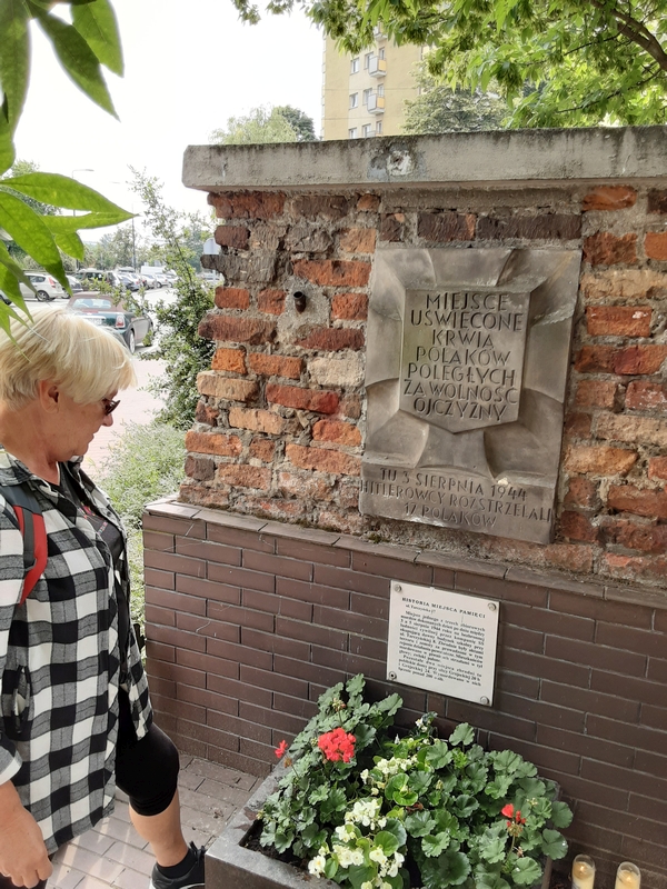 Jolanta 
reading the plaque, which is attached to what looks like the remains of a building.