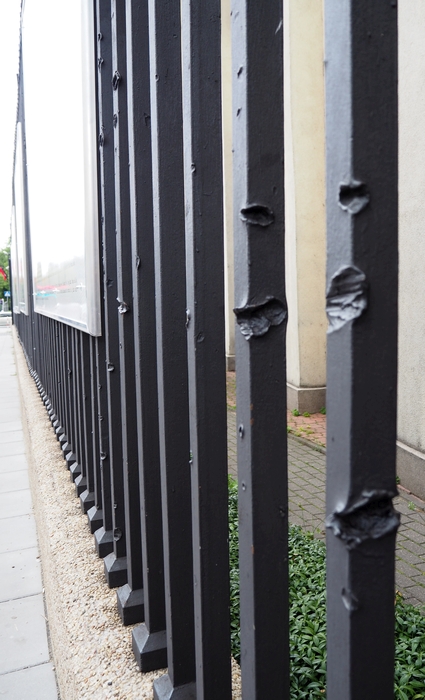 black-painted railings at an angle into the distance, showing bullet markings
