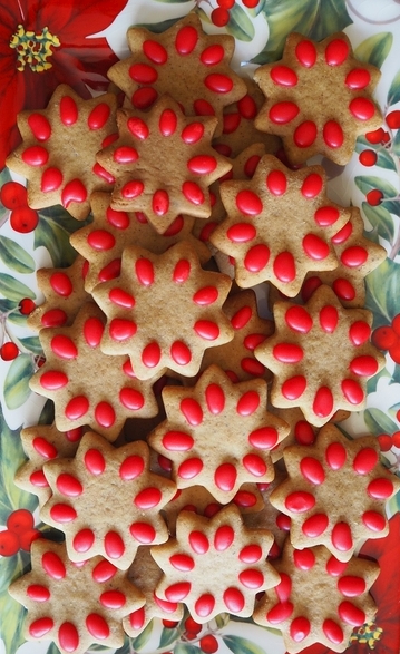A pohutukawa Christmas plate with star-shaped pierniczki with red blobs of icing on the stars. 